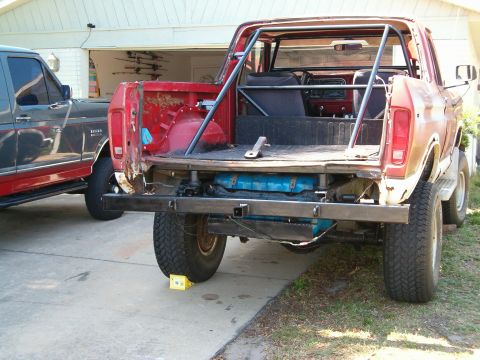 1979 Ford Bronco - Rear view of a 1979 Ford Bronco with a custom roll cage and bumper, parked next to another truck.
