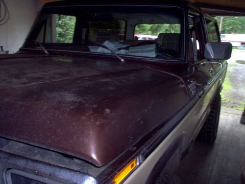 1979 Ford Bronco - A weathered brown and tan Ford Bronco is parked inside a garage, showing its front 3/4 view.