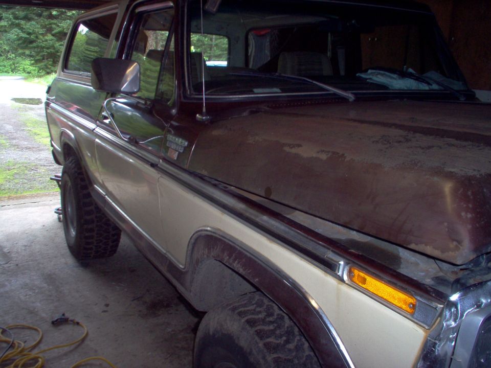 Two-tone brown and tan Ford Bronco SUV parked in a garage, passenger side view.