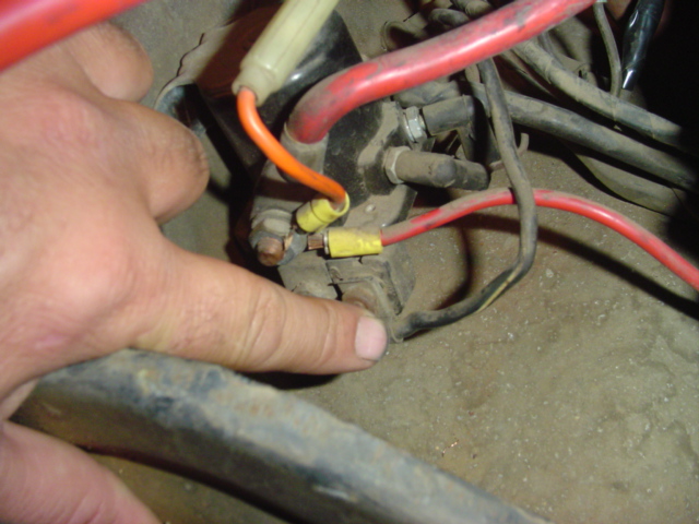 Close-up of starter solenoid wiring with a finger pointing to a connection