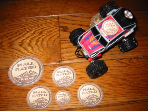 1985 Ford Bronco - A toy monster truck with "Mall Rated 4x4" branding is displayed with several matching decals on a wooden surface.