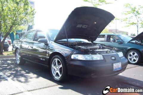 1998 Ford Taurus - Black 1998 Ford Taurus SHO on display with its hood open, parked outdoors.