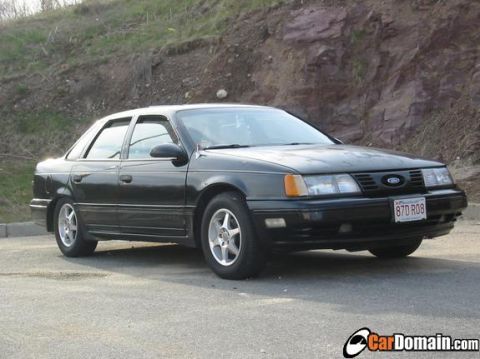 1998 Ford Taurus - This black sedan is parked outdoors with a rocky hillside behind it. The license plate is visible.