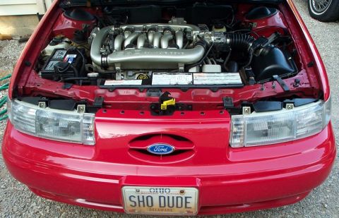 1998 Ford Taurus - Front view of a 1998 Ford Taurus showing the engine compartment and the Ford emblem on the grille.