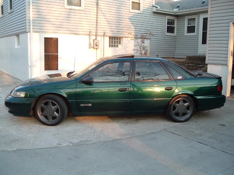 Green sedan parked in driveway. It has a sunroof and aftermarket wheels