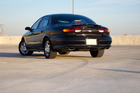 1998 Ford Taurus - Rear view of a black 1998 Ford Taurus sedan on a concrete surface.