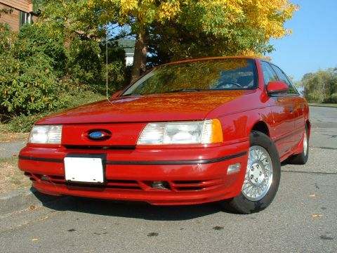 1998 Ford Taurus - This red sedan's body style suggests it is from the early 1990s, not a 1998 model.