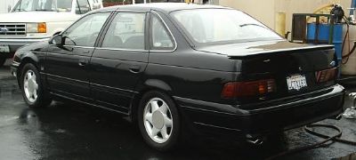 1998 Ford Taurus - Rear view of a black 1998 Ford Taurus sedan with a spoiler.