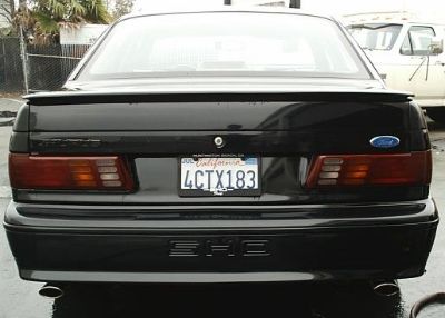 1998 Ford Taurus - The rear of a black sedan is shown, a spoiler and a California license plate.