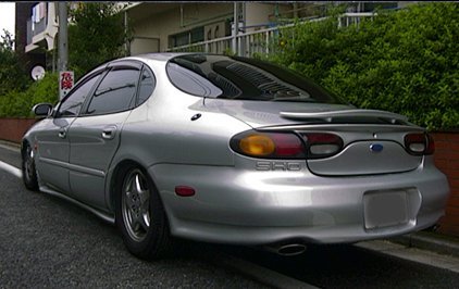 1998 Ford Taurus - A silver 1998 Ford Taurus sedan is viewed from the rear 3/4 angle on a street.