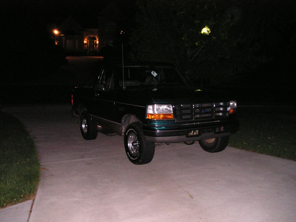 Dark green 1990s Ford extended-cab pickup on a driveway at night