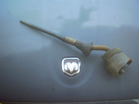 1991 Ford Crown Victoria - A Dodge Ram emblem is visible on a gray surface next to a worn metallic vehicle part.