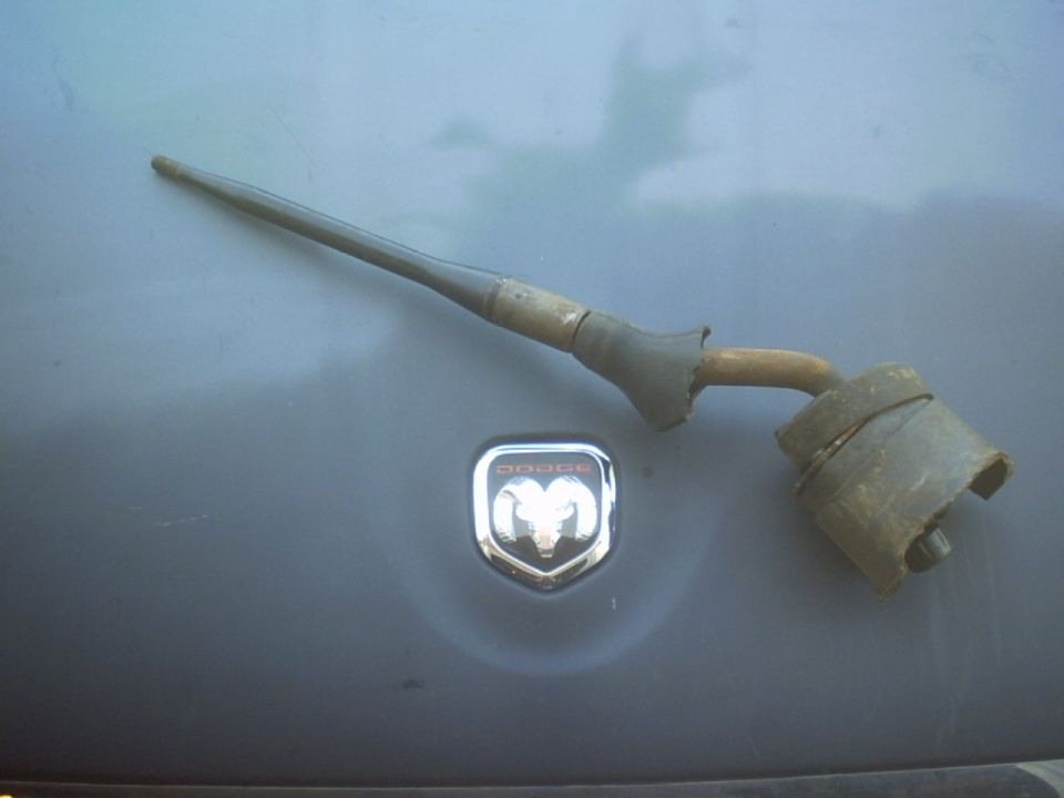 Dodge Ram emblem on a gray surface with a metallic part resting on it
