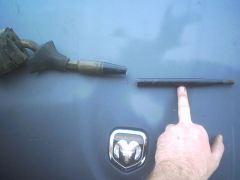 1991 Ford Crown Victoria - A Dodge emblem is visible on a dark surface next to a car part.