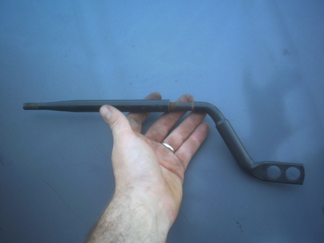 Hand holding a bent metal rod with two circular holes at one end