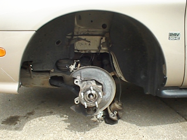 Front wheel assembly removed, showing brake rotor and suspension components. Vehicle has a '24V DOHC' badge