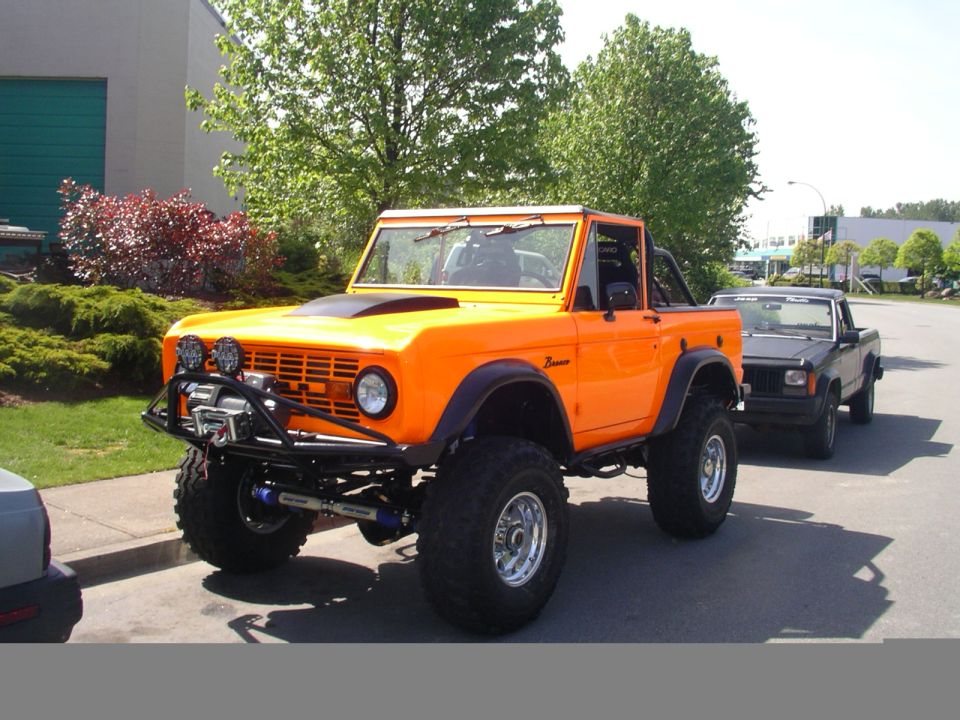 Orange Ford Bronco with lifted suspension, off-road tires, winch, and aftermarket bumper
