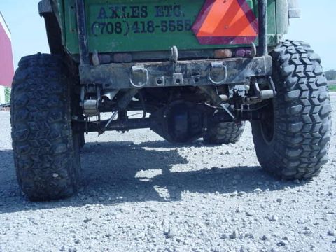 1992 Ford Bronco - This photo shows the rear axle and large off-road tires of a green vehicle, with contact information visible on the tailgate.