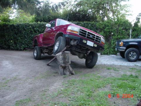 1992 Ford F-150 - A 1992 Ford F-150 is shown with its front end elevated on a log, next to another dark-colored truck.