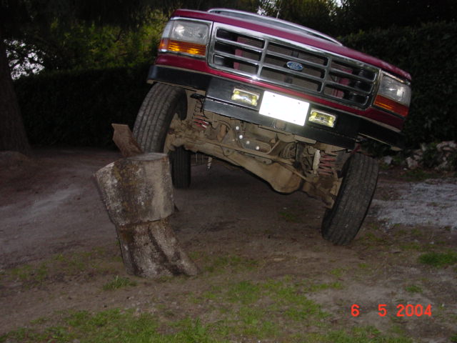 1992 Ford F-150 front end angled over a large wooden log obstacle