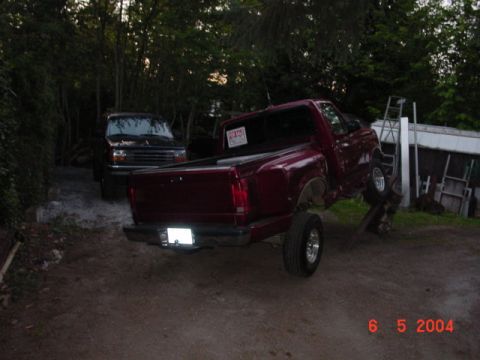 1992 Ford F-150 - A red pickup truck is parked in a yard with a dark colored SUV behind it.