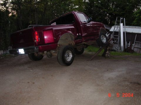 1992 Ford F-150 - A red 1992 Ford F-150 pickup truck is positioned on ramps, with its front wheels elevated.