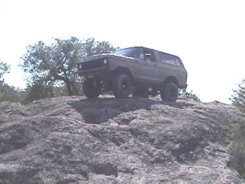 1978 Ford Bronco - This 1978 Ford Bronco navigates a rocky terrain, its front-right side visible against a bright sky.