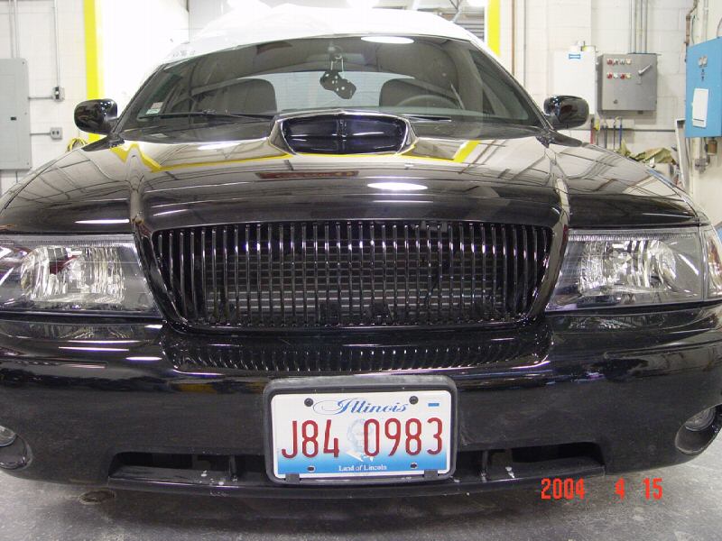 Black sedan front view showing custom grille and hood scoop. Illinois license plate J84 0983 visible