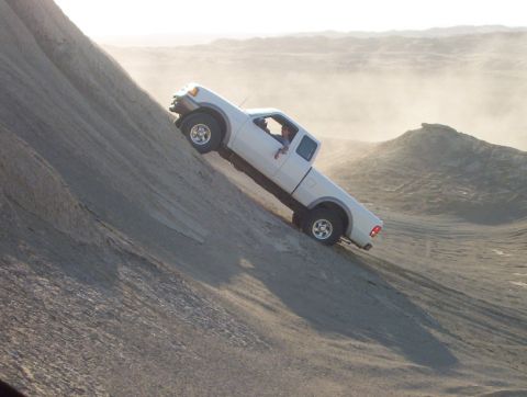 2000 Ford F-450 - A white pickup truck navigates a challenging incline on a dusty, barren landscape.