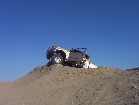 2000 Ford F-450 - A 2000 Ford F-450 is stuck on a sand dune with its driver's door open.