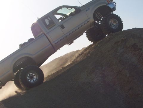 2000 Ford F-450 - Modified 2000 Ford F-450 pickup truck navigates a steep dirt incline.