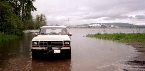 1978 Ford Bronco - A 1979 Ford F-Series truck navigates through a flooded area with industrial buildings in the background.