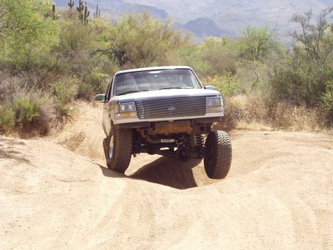 1993 Ford Bronco - A lifted 1992 Ford Bronco navigates a dusty trail through a desert environment.