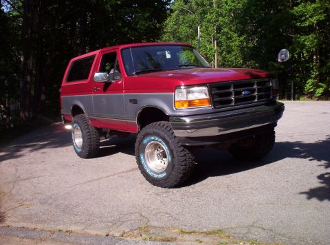 1995 Ford Bronco - This 1995 Ford Bronco features a two-tone red and grey paint scheme and is equipped with aftermarket wheels and tires.