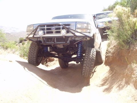 1993 Ford Bronco - Modified Ford Bronco navigating a dirt trail with a custom front bumper and lifted suspension.