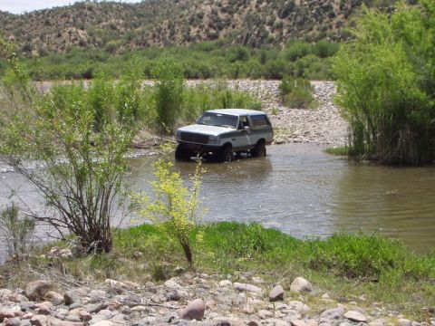 1993 Ford Bronco - Ford Bronco navigates a river crossing in a natural landscape.