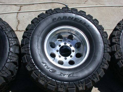 1996 Ford Bronco - Close-up view of off-road tires and chrome rims, with visible text branding.