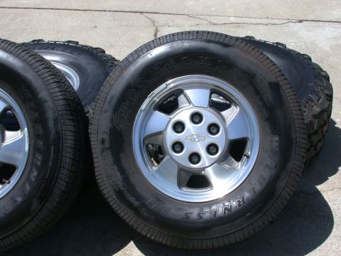 1996 Ford Bronco - Set of four tires and rims, each with a Chevrolet emblem on the hub. The tires are Firestone Wilderness LE.