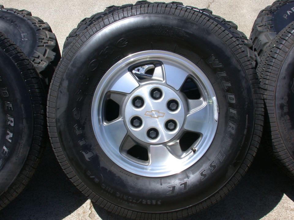 Four tires and wheels, one with a Chevrolet logo on the hub