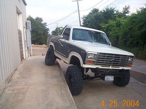 1986 Ford Bronco - This lifted Ford pickup truck is parked on a concrete ramp, showing off its large tires and modified suspension.