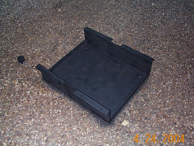 Fabricated black steel fuel tank skid plate lying on a concrete floor