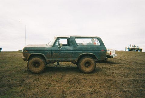 1978 Ford Bronco - A muddy 1978 Ford Bronco sits in a muddy field, with other vehicles visible in the background.