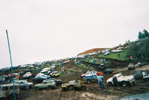 1978 Ford Bronco - A large gathering of off-road vehicles and spectators on a muddy hillside during an event.