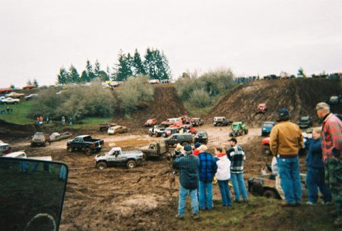 1978 Ford Bronco - Off-road vehicles navigate muddy terrain during an event, with spectators observing the action.