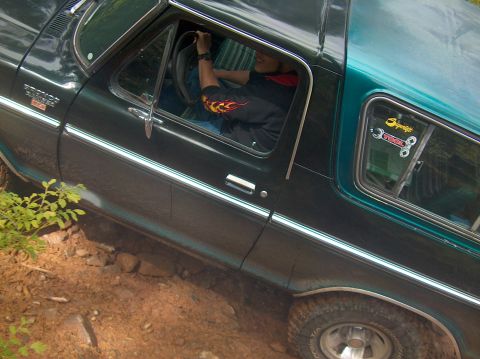 1978 Ford Bronco - Driver's perspective from inside a green 1978 Ford Bronco, showing the interior and the vehicle's side as it navigates rough terrain.
