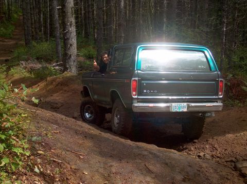 1978 Ford Bronco - This 1978 Ford Bronco navigates a wooded dirt trail, showing its rear profile and turquoise top.