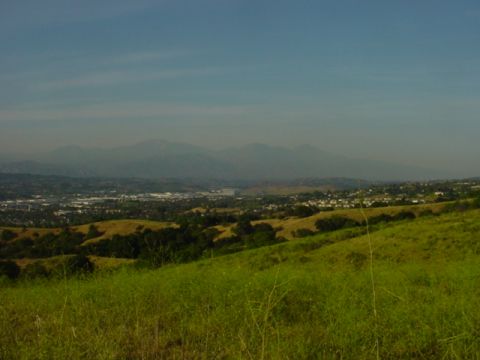 1988 Ford Bronco - A wide view of a valley and mountains under a hazy sky, with foreground hills covered in grass.