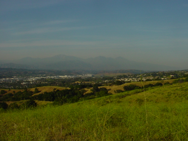 Hazy mountain landscape over a distant town with grassy hills in the foreground