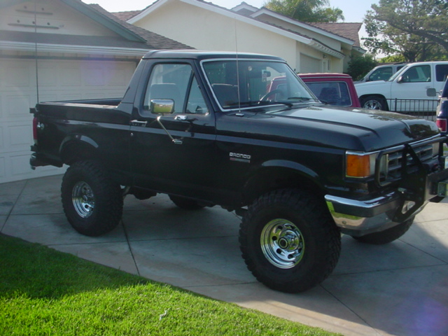 Black Ford Bronco with aftermarket bull bar and lifted suspension, parked in a driveway
