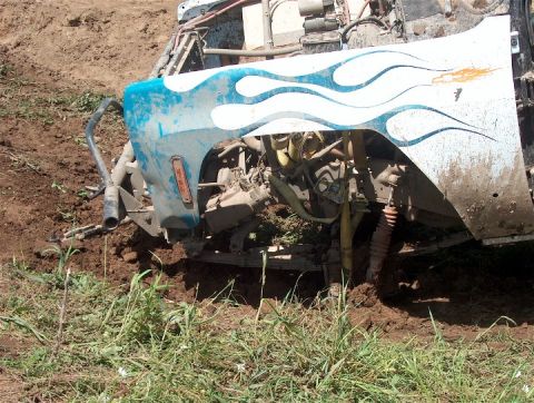1979 Ford Bronco - Vehicle stuck in the mud, front fender damaged with blue flame graphics.